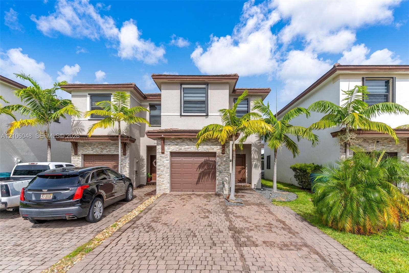 25134 SW 108th Court, Homestead, FL 33032 Stucco exterior with stone veneer accents, paver driveway, single-car garage, and mature palm landscaping