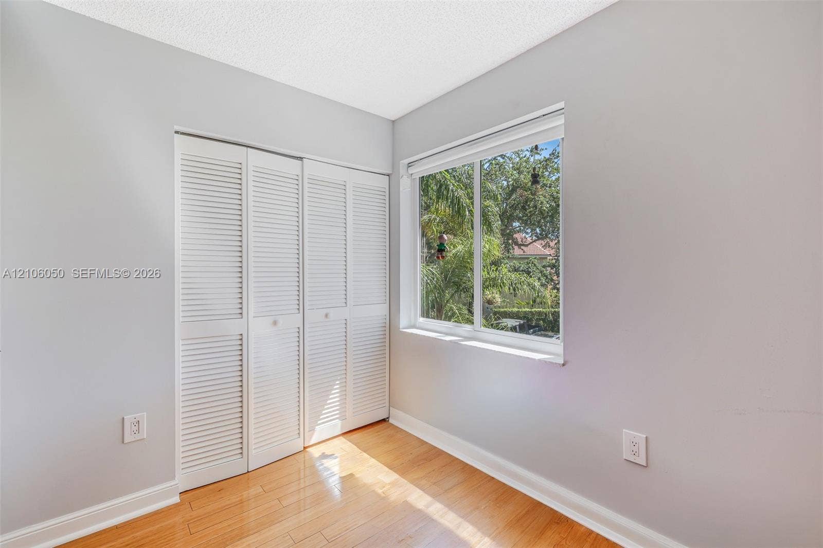1065 Weeping Willow Way, #0, Hollywood, Hollywood, FL 33019 Neutral wall finishes, wood-finish flooring, and white louvered-style closet doors, featuring a sliding window with outdoor greenery