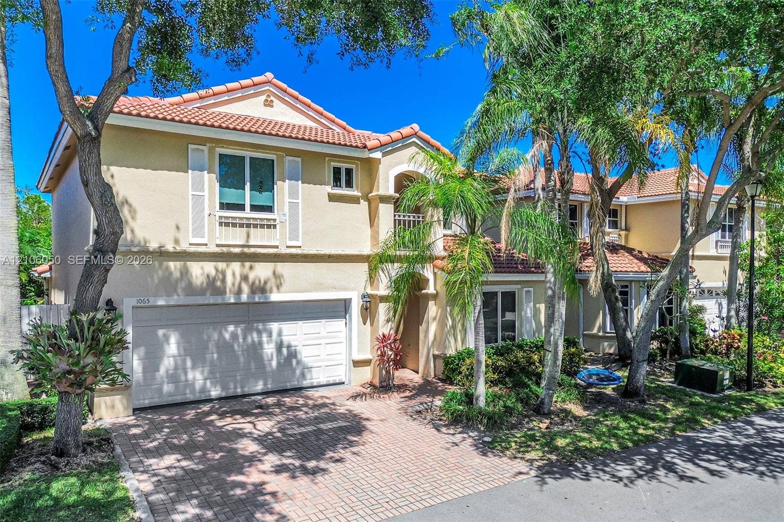 1065 Weeping Willow Way, #0, Hollywood, Hollywood, FL 33019 Stucco exterior featuring a clay tile roof, arched entryway, brick-paver driveway, and an attached two-car garage