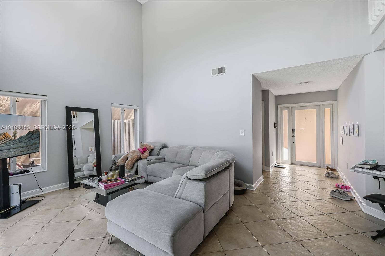1065 Weeping Willow Way, #0, Hollywood, Hollywood, FL 33019 High-ceilinged room featuring ceramic tile flooring, dual windows, and an entryway with a glass-panel door and sidelights