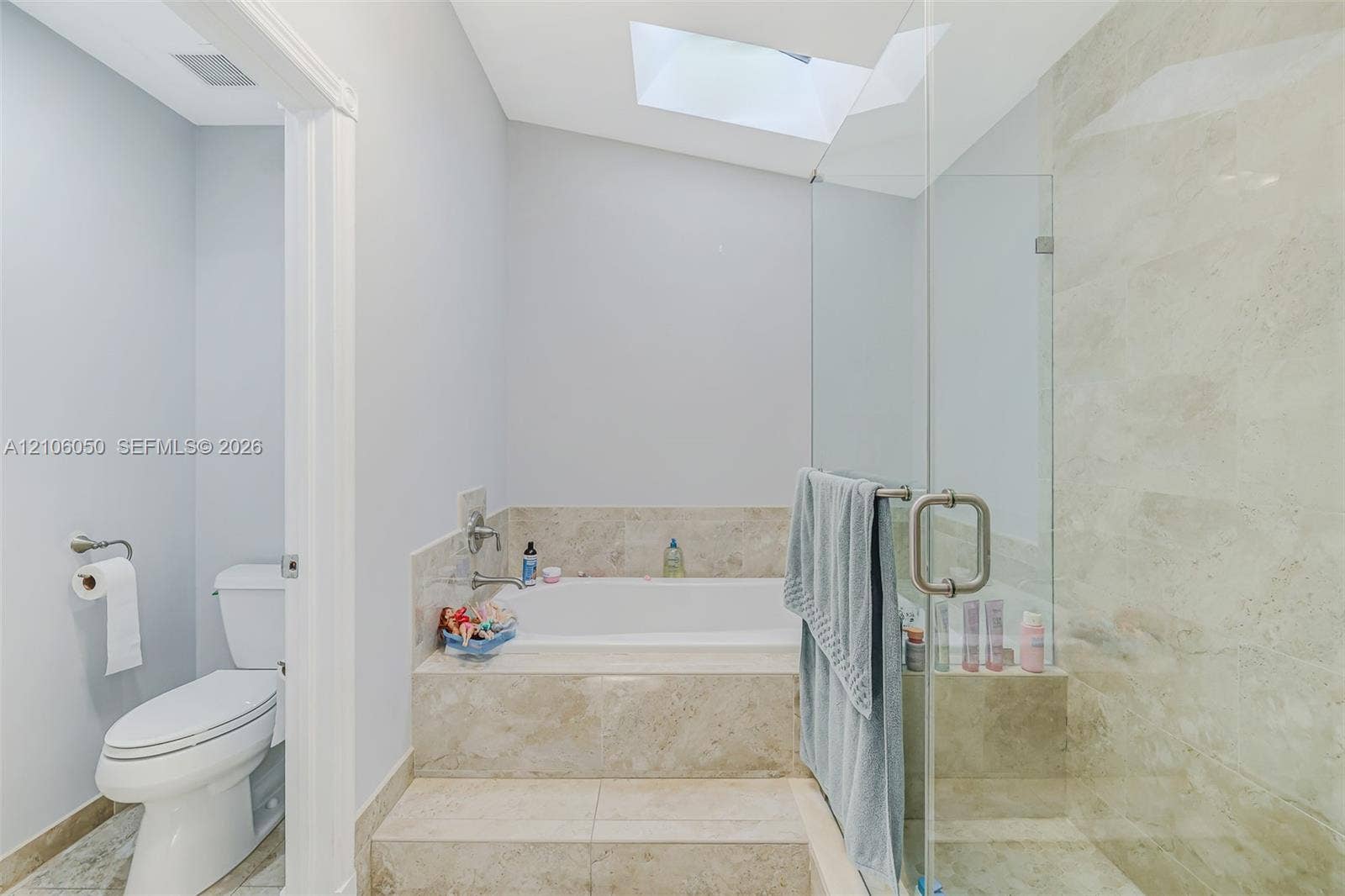 1065 Weeping Willow Way, #0, Hollywood, Hollywood, FL 33019 Skylit bathroom featuring a tiled platform soaking tub, separate glass-enclosed shower, stone-finish surround, and a porcelain toilet