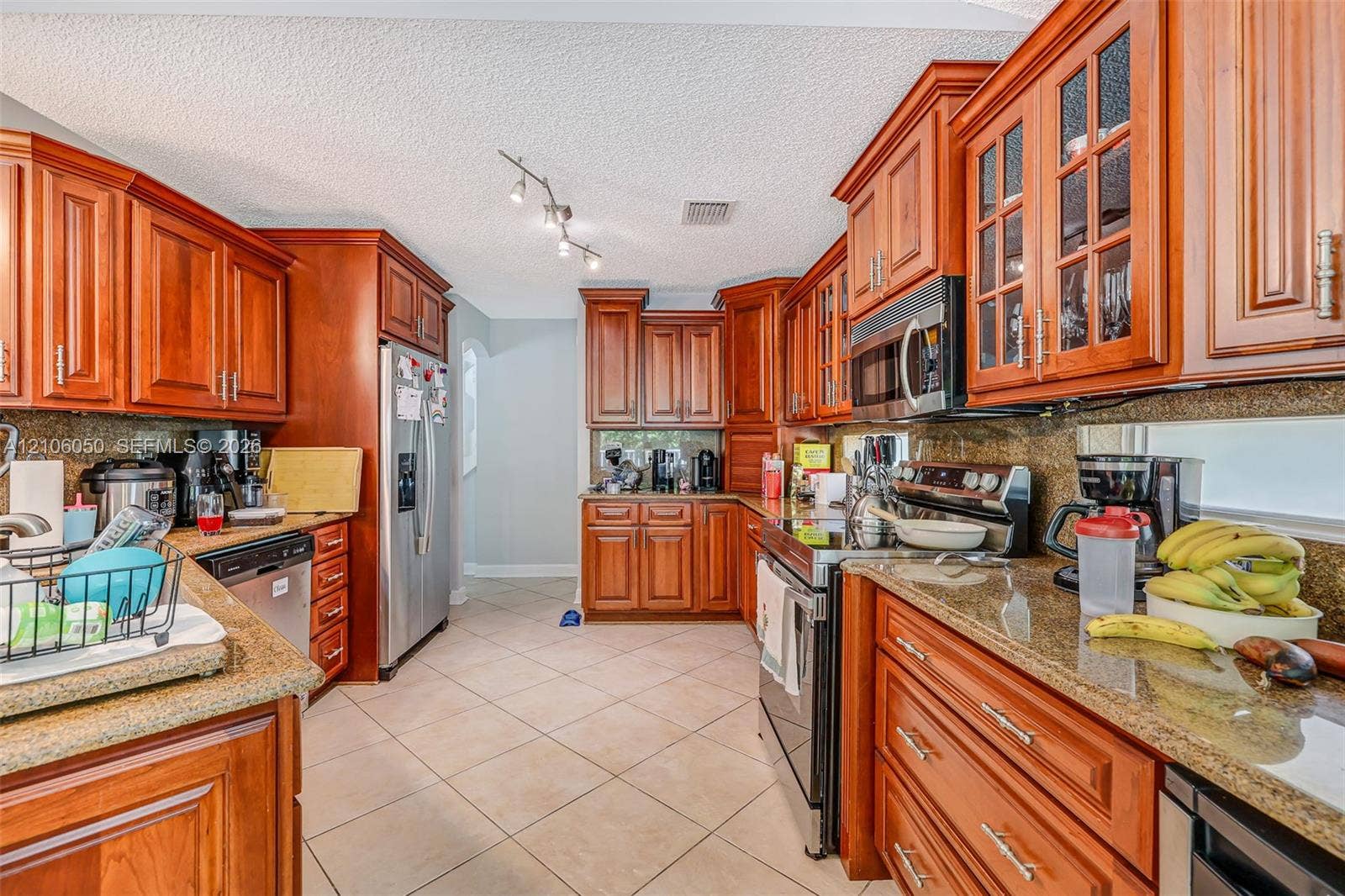 1065 Weeping Willow Way, #0, Hollywood, Hollywood, FL 33019 Kitchen featuring stained wood cabinetry with glass-panel upper doors, stone-finish countertops, stainless steel appliances, and ceramic tile flooring