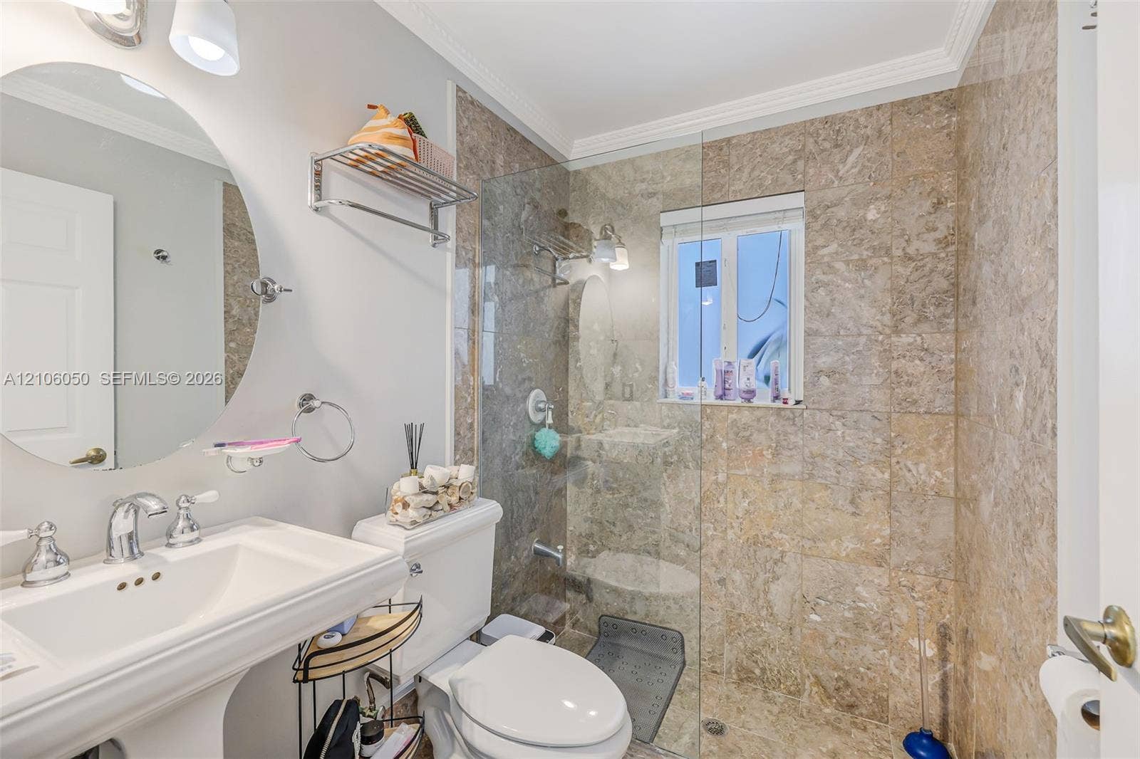1065 Weeping Willow Way, #0, Hollywood, Hollywood, FL 33019 Bathroom featuring a wall-mounted oval mirror, porcelain pedestal sink, chrome hardware, and a glass-enclosed walk-in shower finished with full-height stone-patterned wall tile