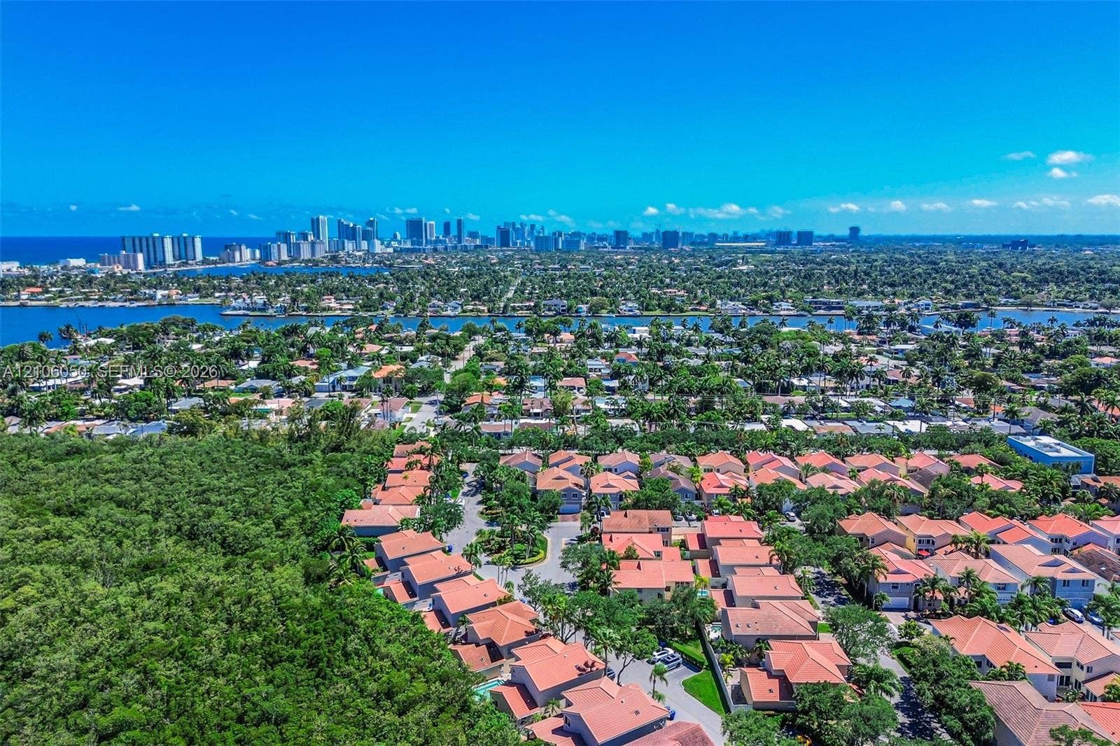 1065 Weeping Willow Way, #0, Hollywood, Hollywood, FL 33019 Aerial perspective featuring a residential community with clay tile roofing, dense surrounding vegetation, and a coastal skyline backdrop