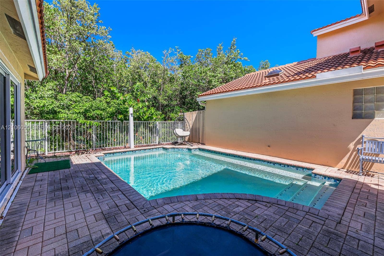 1065 Weeping Willow Way, #0, Hollywood, Hollywood, FL 33019 In-ground pool with built-in stairs, enclosed by metal perimeter fencing, featuring paver hardscaping and a clay tile roof