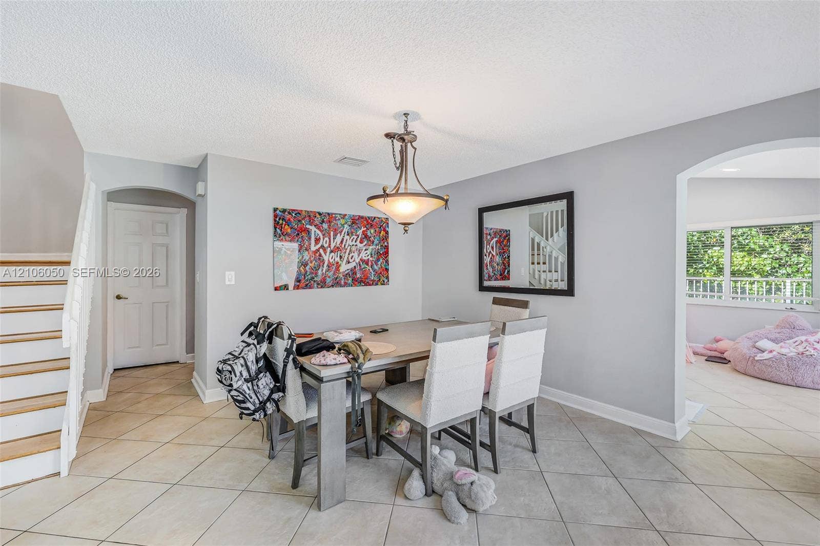 1065 Weeping Willow Way, #0, Hollywood, Hollywood, FL 33019 Dining space featuring neutral tile flooring, arched entryways, a central metal pendant light fixture, and stairs with wood treads