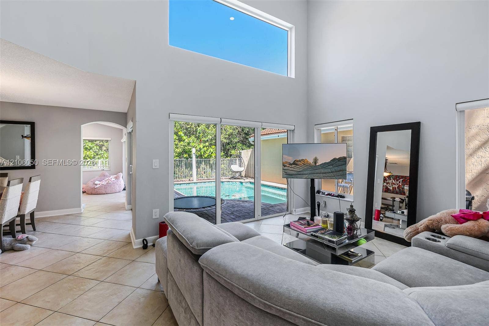 1065 Weeping Willow Way, #0, Hollywood, Hollywood, FL 33019 Double-height ceiling with clerestory windows, tile flooring, and oversized sliding glass doors opening to a screened pool enclosure