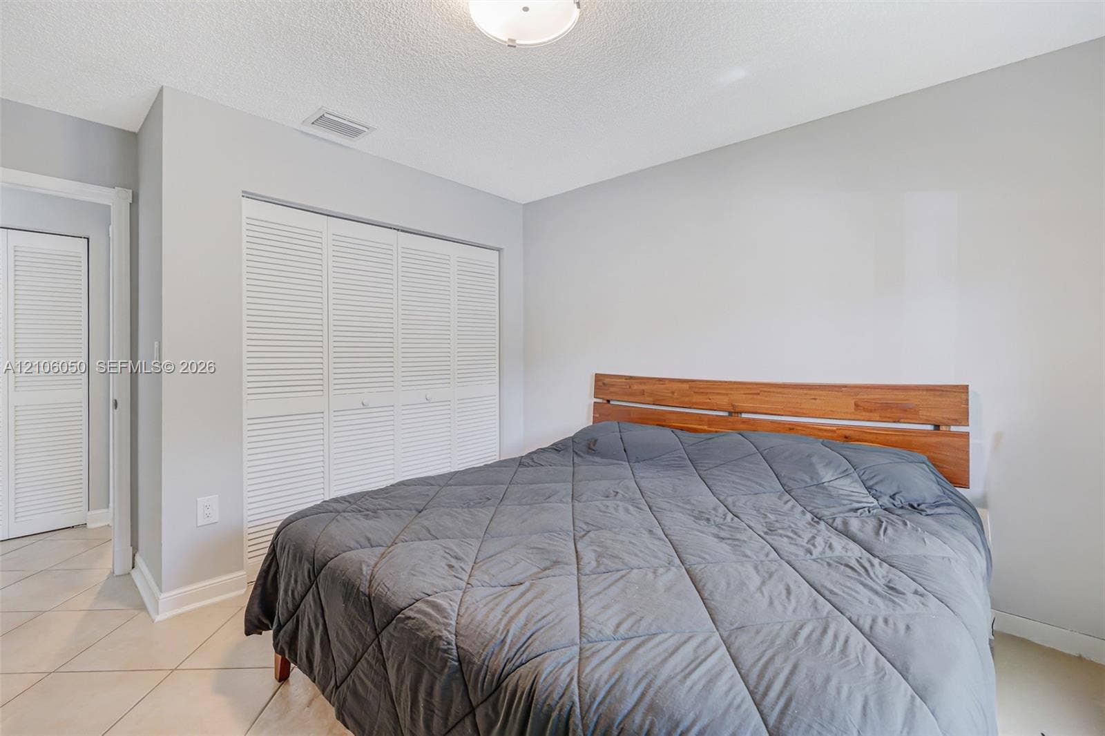 1065 Weeping Willow Way, #0, Hollywood, Hollywood, FL 33019 Neutral-toned interior featuring louvered closet doors, tile flooring, and a flush-mount ceiling light fixture