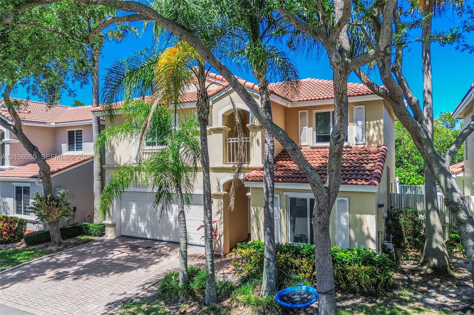 1065 Weeping Willow Way, #0, Hollywood, Hollywood, FL 33019 Two-story residence featuring a stucco facade, red tile roof, arched entryway, second-story balcony with decorative railing, and a brick-paver driveway