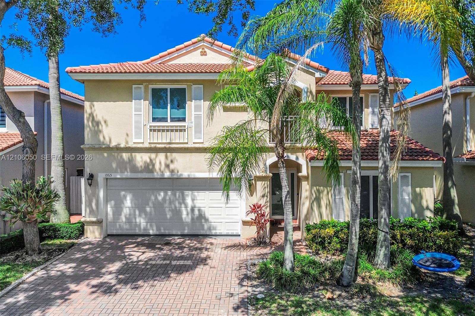1065 Weeping Willow Way, #0, Hollywood, Hollywood, FL 33019 Two-story exterior featuring a stucco facade, red tile roof, arched entryway, second-story balcony, and brick-paver driveway