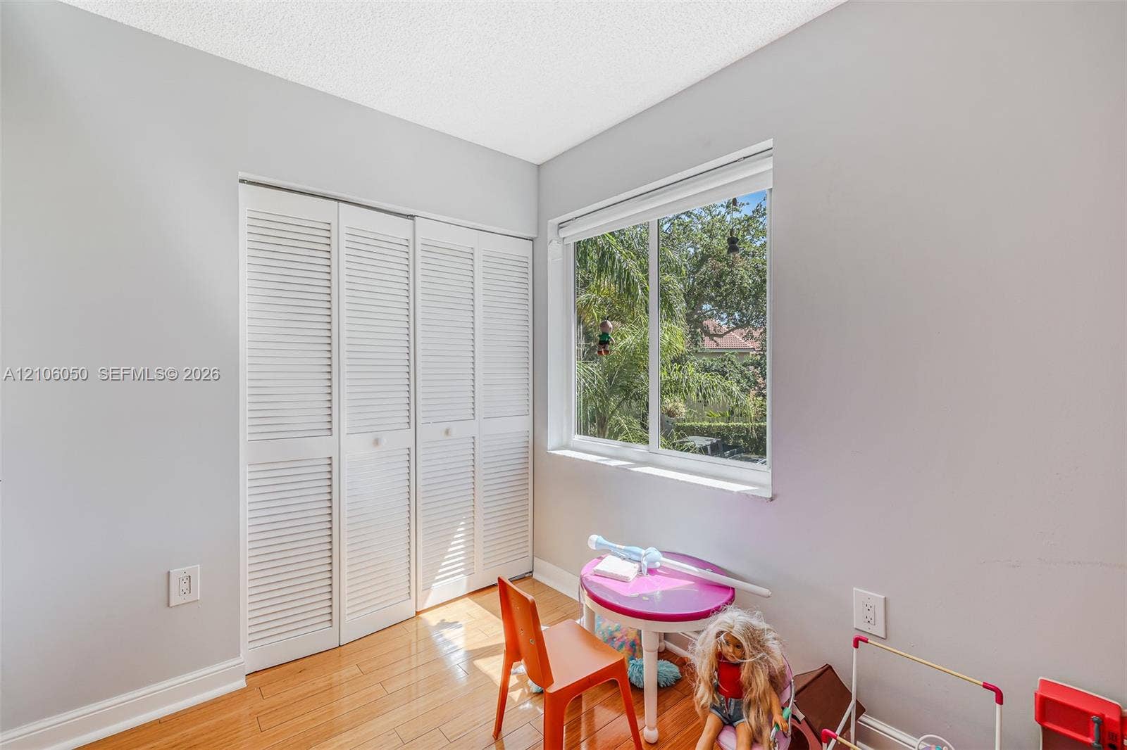 1065 Weeping Willow Way, #0, Hollywood, Hollywood, FL 33019 Bedroom featuring wood-finish flooring, a double-panel louvered closet, and a large horizontal window providing exterior greenery