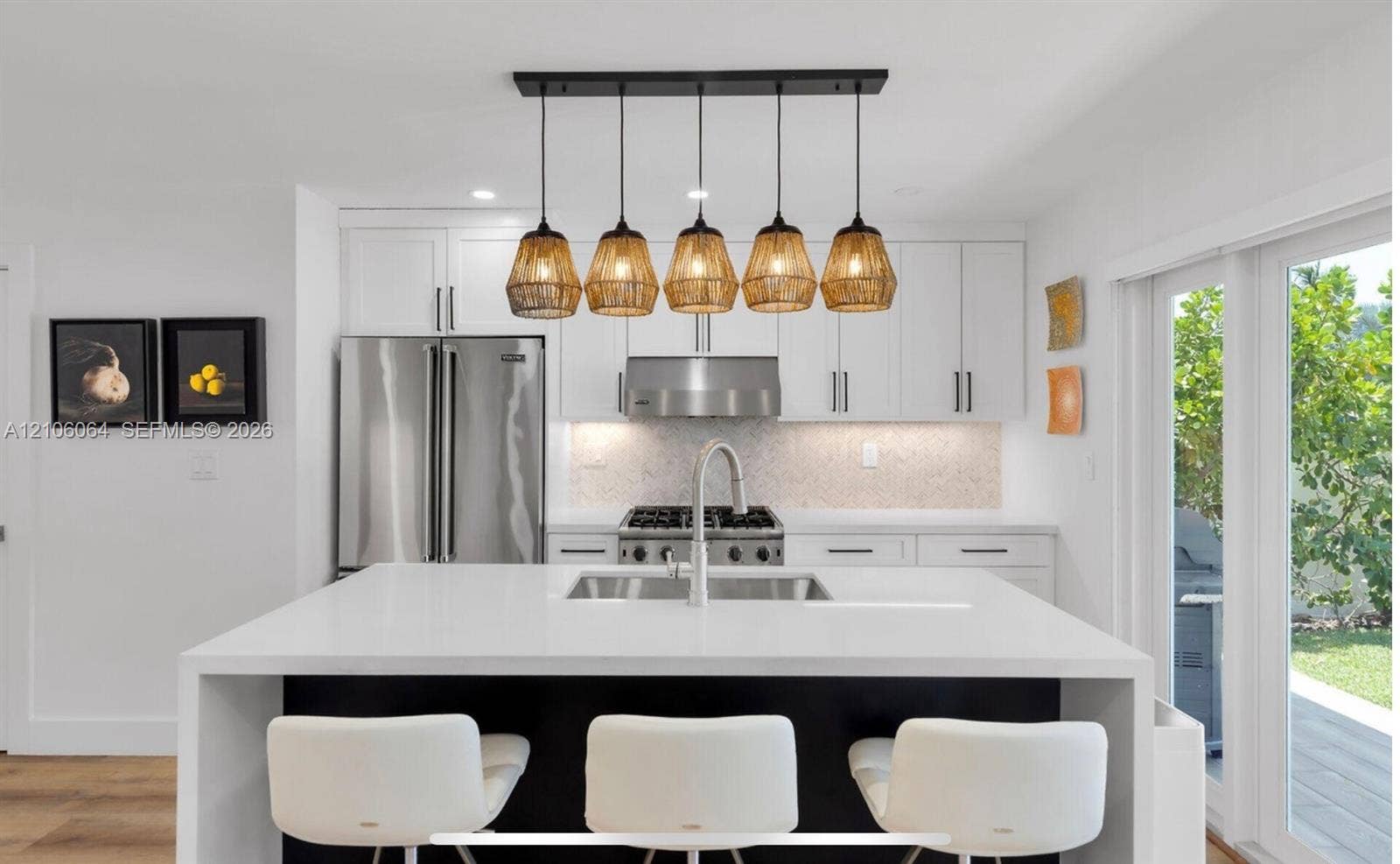 179 Azalea Street, Islamorada, FL 33070 Kitchen featuring a central island with a solid surface countertop, white shaker-style cabinetry, stainless steel professional-grade appliances, and a linear multi-pendant lighting fixture