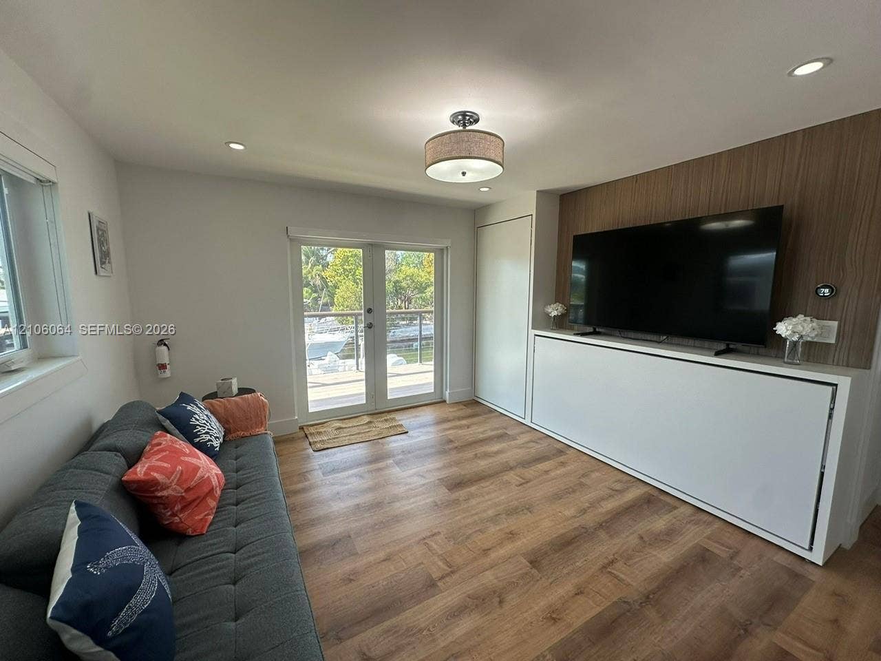 179 Azalea Street, Islamorada, FL 33070 Wood-finish flooring, built-in cabinetry with integrated wall paneling, recessed lighting, drum-style flush mount ceiling fixture, and glass-paned double doors