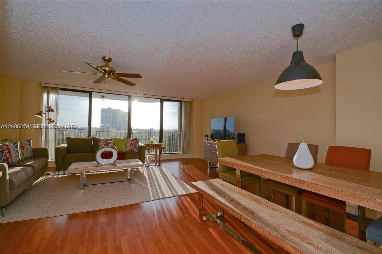 300 Three Islands Boulevard, #308, Hallandale Beach, Hallandale Beach, FL 33009 Open floor plan featuring wood-finish flooring, floor-to-ceiling glass sliding doors, a metallic ceiling fan, and a matte black pendant light fixture