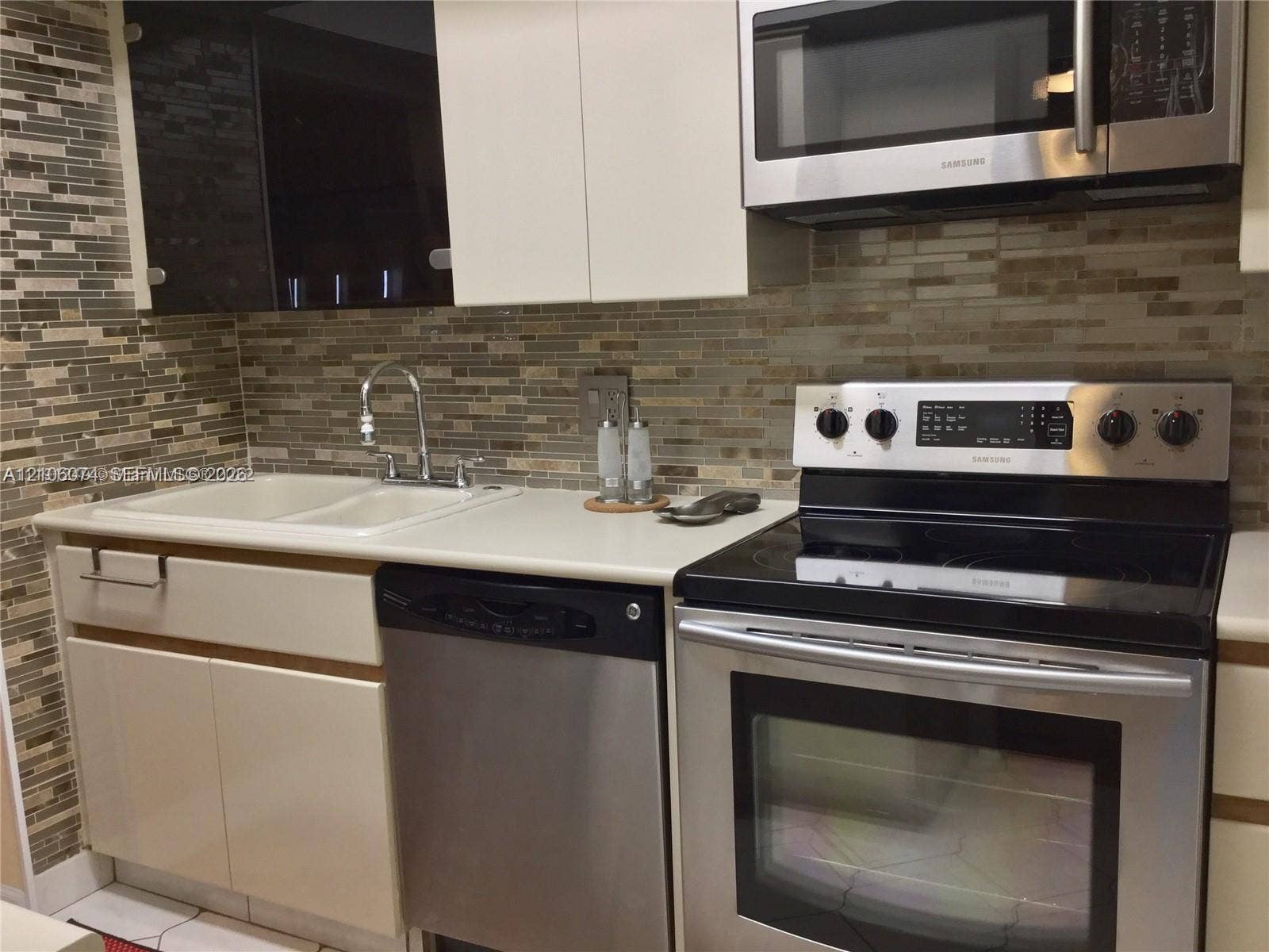 300 Three Islands Boulevard, #308, Hallandale Beach, Hallandale Beach, FL 33009 Kitchen featuring stainless steel appliances, dual-basin sink with arched faucet, mosaic tile backsplash, and two-tone flat-panel cabinetry