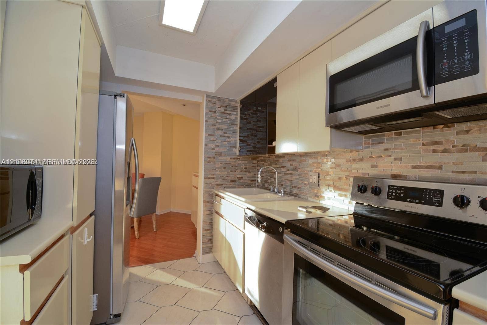 300 Three Islands Boulevard, #308, Hallandale Beach, Hallandale Beach, FL 33009 Kitchen featuring flat-panel cabinetry, stainless steel appliances, multi-tonal stacked stone backsplash, solid surface countertops, and diagonal ceramic tile flooring