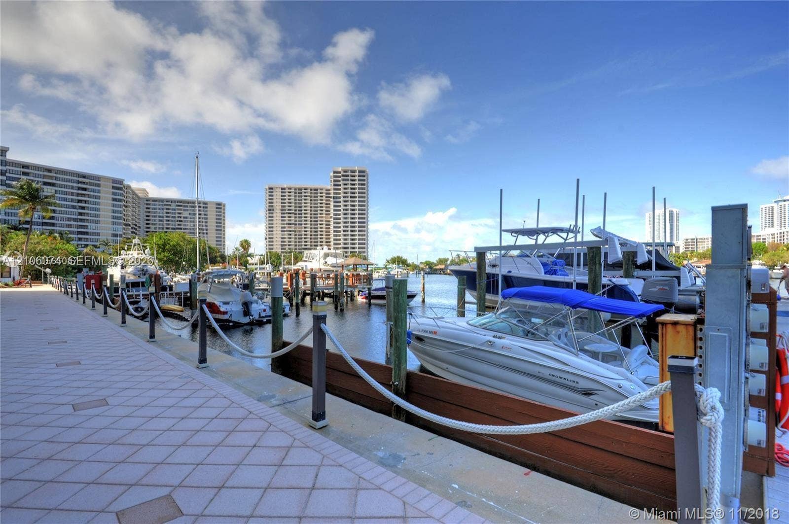 300 Three Islands Boulevard, #308, Hallandale Beach, Hallandale Beach, FL 33009 Waterfront boat slip featuring wood bulkhead, dockside pedestals, and rope railing with metal posts along a paved promenade
