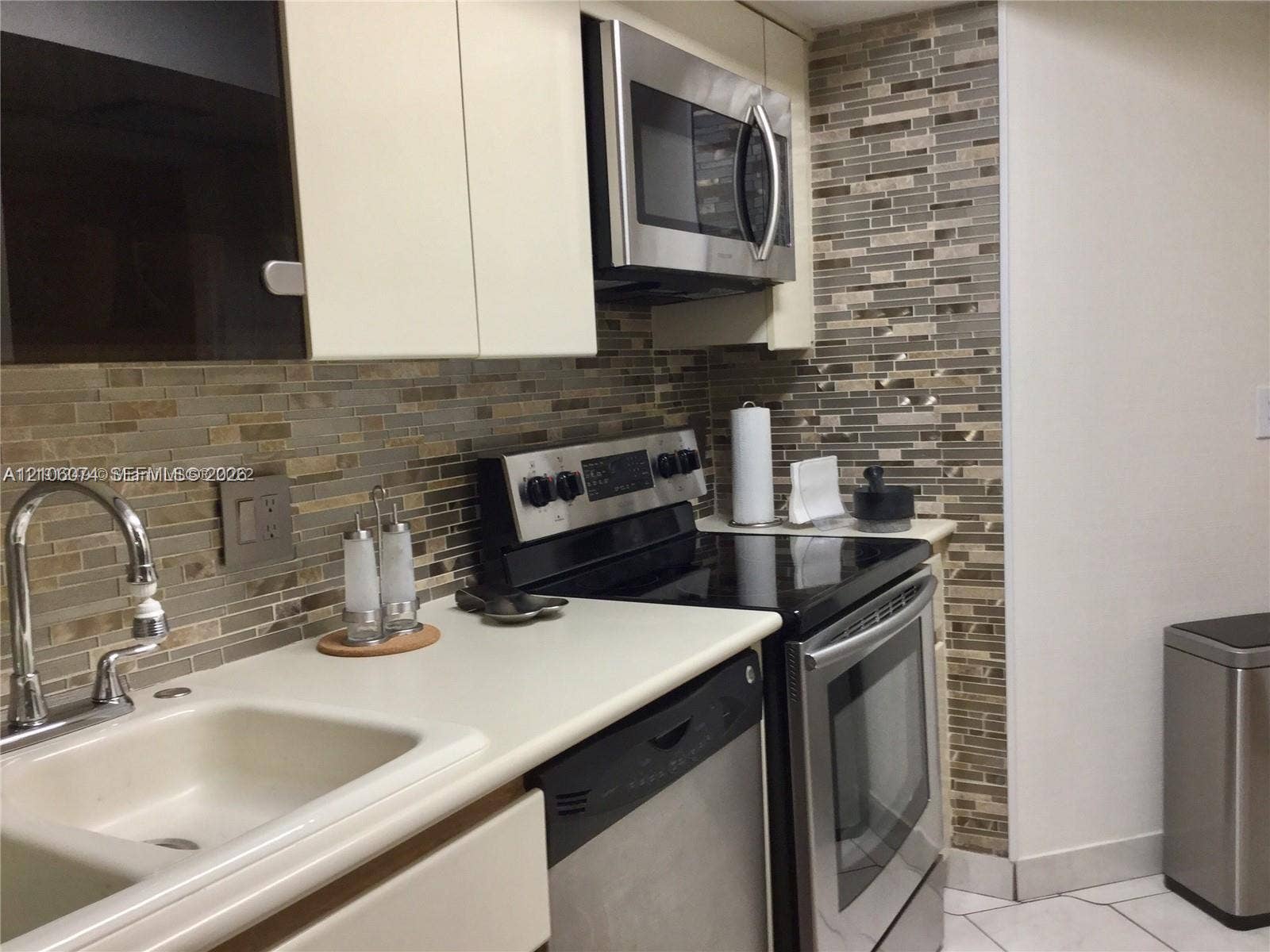 300 Three Islands Boulevard, #308, Hallandale Beach, Hallandale Beach, FL 33009 Kitchen featuring stainless steel appliances, multi-tonal linear glass tile backsplash, solid-surface countertops, dual-basin sink with arched faucet, and flat-panel cabinetry