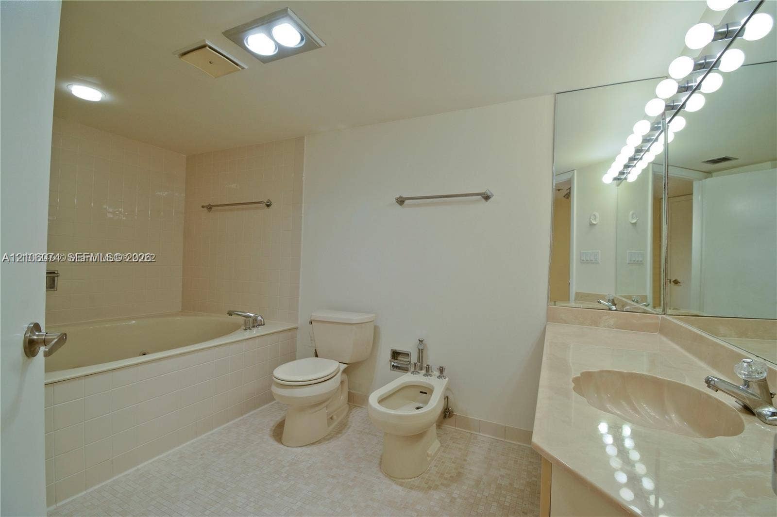 300 Three Islands Boulevard, #308, Hallandale Beach, Hallandale Beach, FL 33009 Bathroom featuring a stone-surface vanity with an integrated scalloped sink, large wall-mounted mirror, deep soaking tub with tile surround, and a bidet