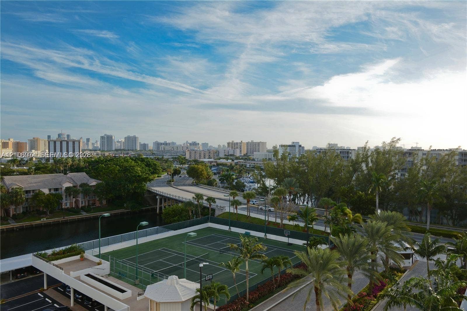 300 Three Islands Boulevard, #308, Hallandale Beach, Hallandale Beach, FL 33009 Tennis court featuring fenced perimeter, integrated lighting, and palm-lined landscaping