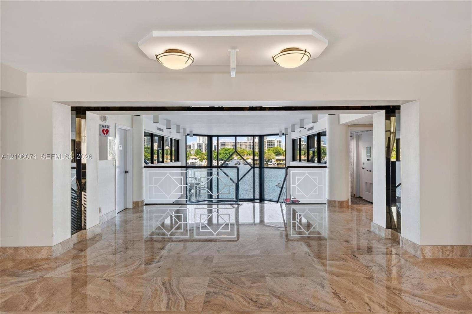 300 Three Islands Boulevard, #308, Hallandale Beach, Hallandale Beach, FL 33009 Polished stone flooring, expansive glass window wall, geometric metal railings, dual recessed ceiling fixtures, and structural columns