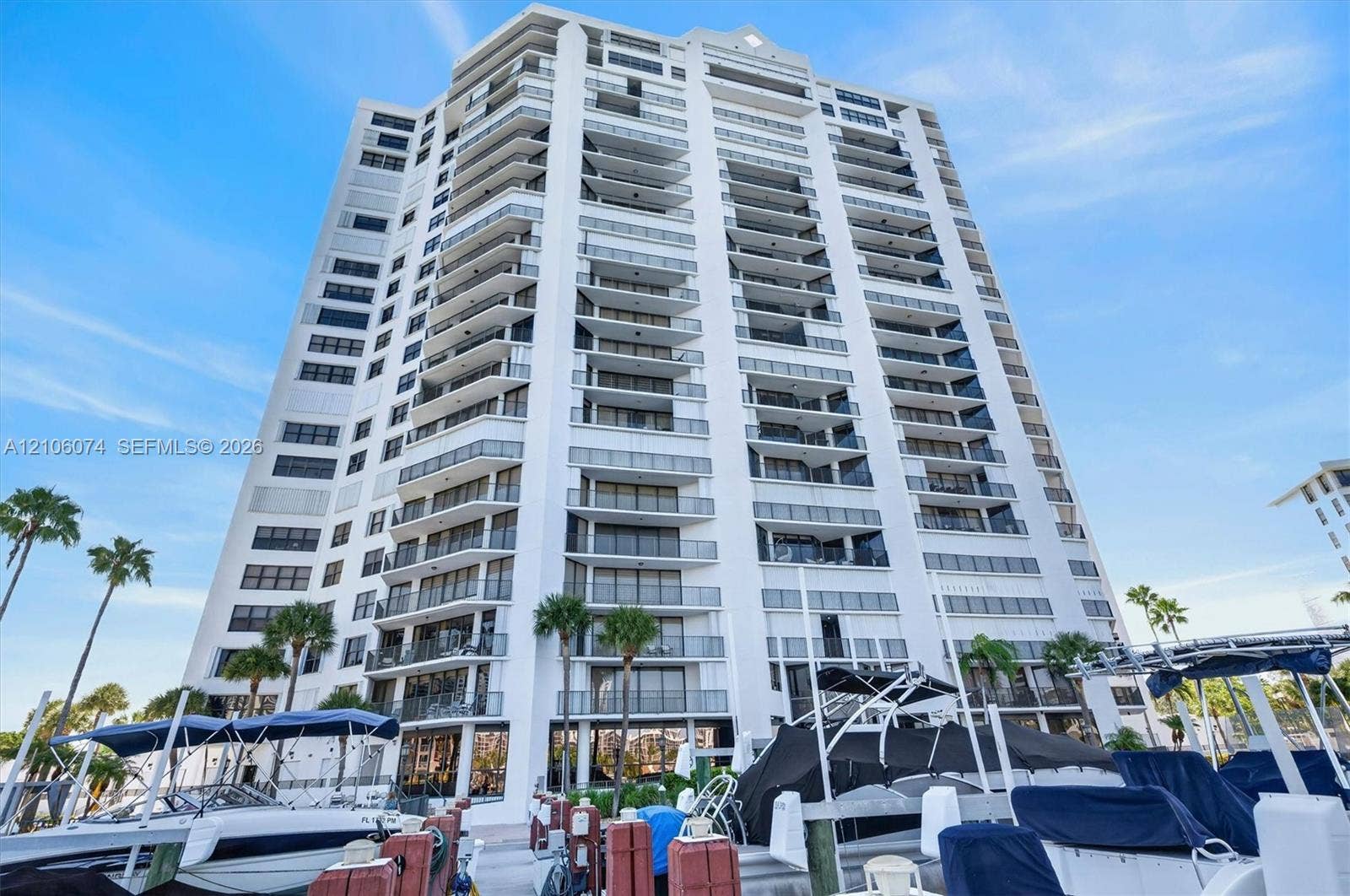 300 Three Islands Boulevard, #308, Hallandale Beach, Hallandale Beach, FL 33009 High-rise building exterior featuring tiered private balconies, glass railings, and a concrete facade, set against a marina with boat docking slips