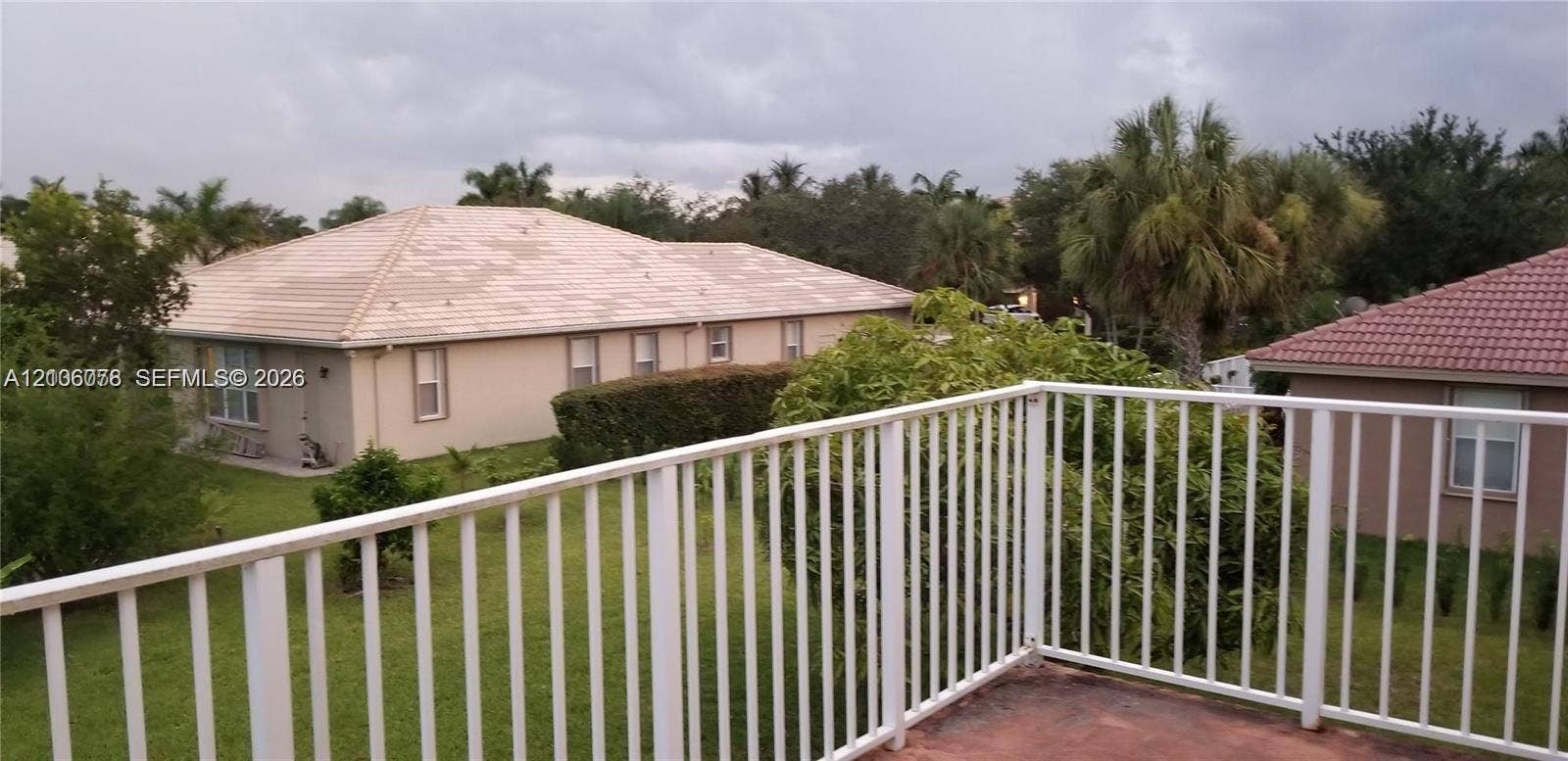 13382 Lakepointe Circle, #0, Cooper City, Cooper City, FL 33330 Elevated balcony featuring a white metal railing and a paved surface, overlooking a grassy yard with mature palms