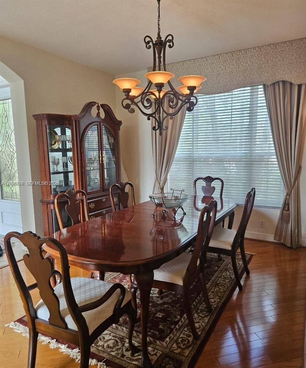 13382 Lakepointe Circle, #0, Cooper City, Cooper City, FL 33330 Dining area featuring wood-finish flooring, a decorative iron chandelier, and a large multi-pane window with arched millwork detail