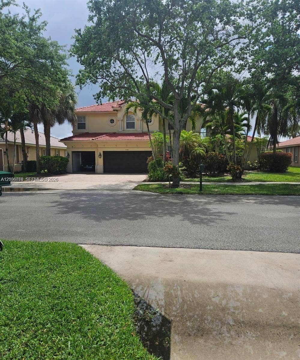 13382 Lakepointe Circle, #0, Cooper City, Cooper City, FL 33330 Two-story residence featuring a terracotta-tiled roof, stucco exterior, attached multi-car garage, and established landscaping