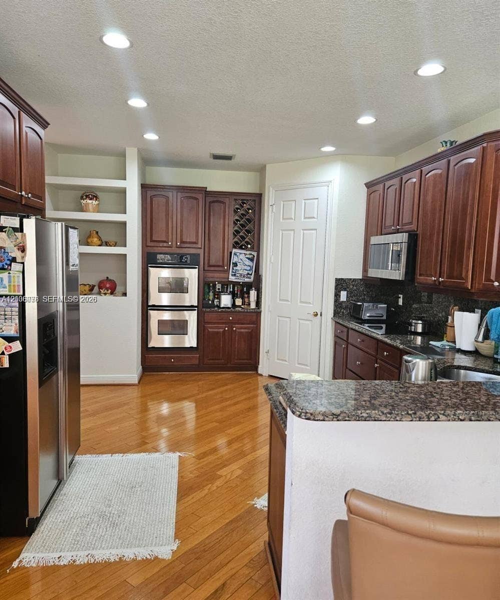 13382 Lakepointe Circle, #0, Cooper City, Cooper City, FL 33330 Kitchen featuring wood cabinetry, recessed lighting, double wall ovens, built-in wine rack, and wood-finish flooring