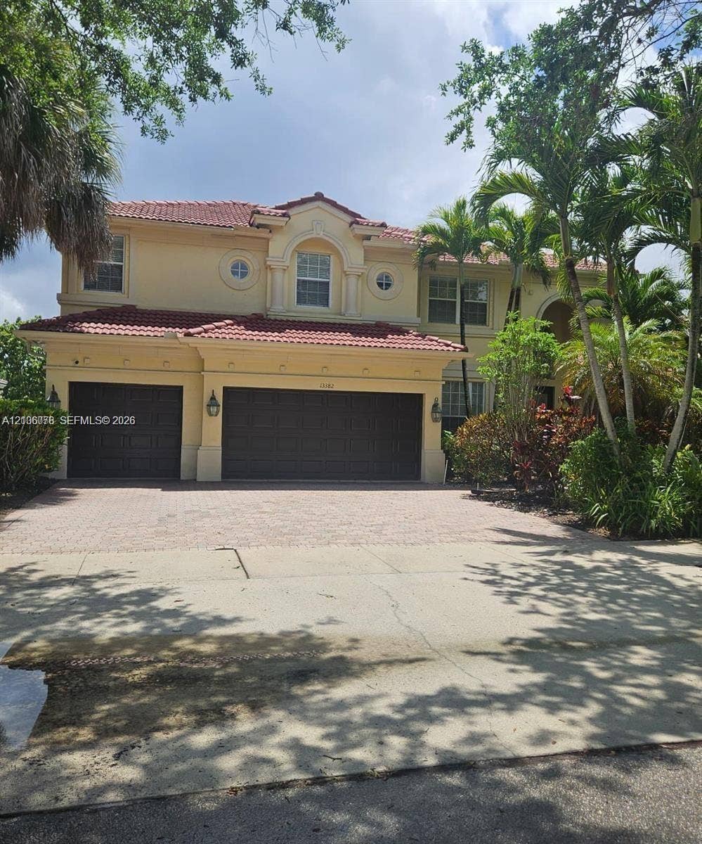 13382 Lakepointe Circle, #0, Cooper City, Cooper City, FL 33330 Two-story stucco exterior featuring a red tile roof, multi-car garage, arched window accents, and paved driveway
