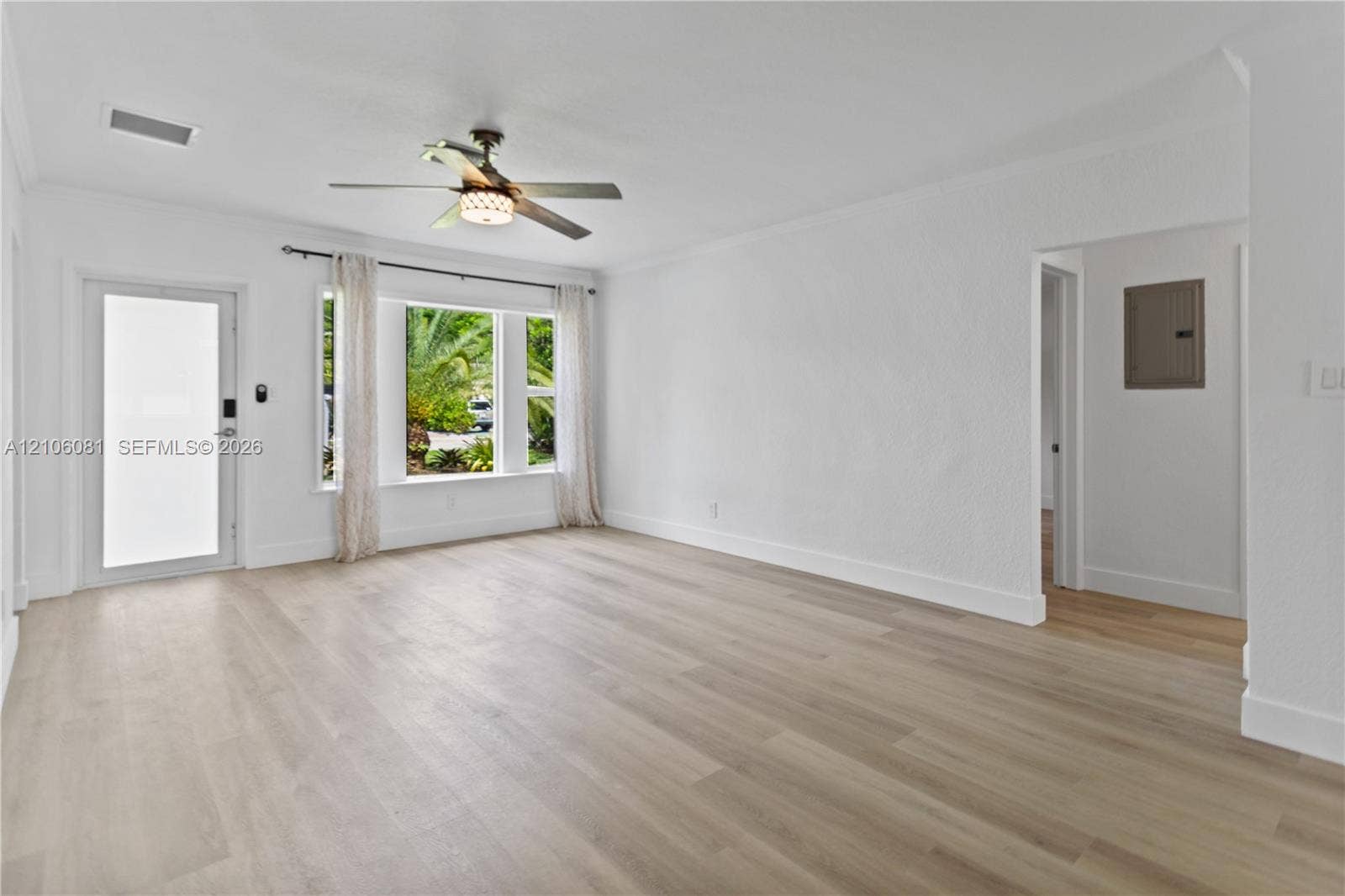 Interior space featuring wood-finish flooring, a multi-pane window, a glass-panel exterior door, and an overhead ceiling fan