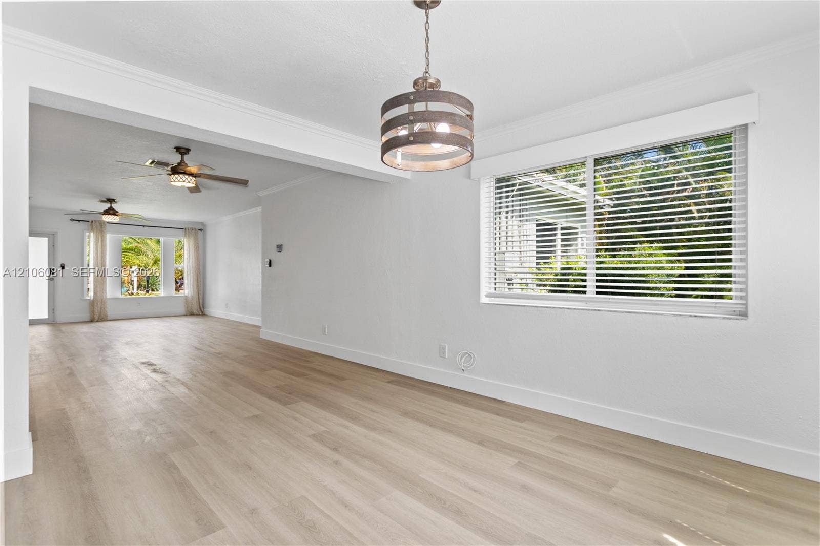 Wood-finish flooring, neutral walls, drum-style pendant lighting, and multiple ceiling fans