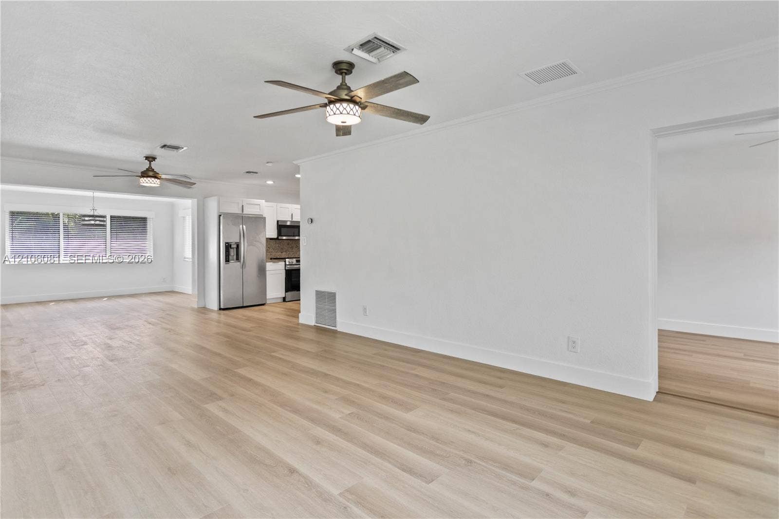 Wood-finish flooring, dual ceiling fans with integrated lighting, and stainless steel kitchen appliances