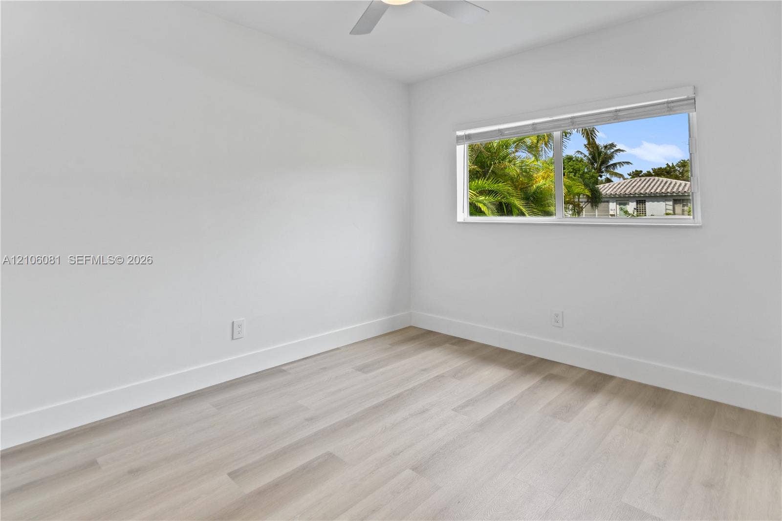 Interior room featuring light wood-finish flooring, neutral walls, a ceiling fan, and a horizontal window with adjustable blinds