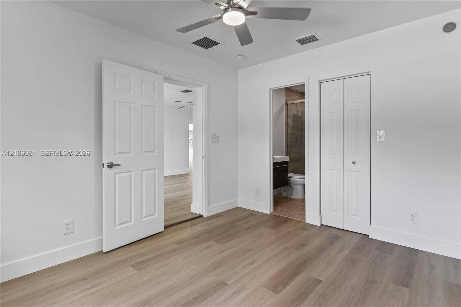 Room featuring wood-finish flooring, a ceiling fan with integrated lighting, dual-panel interior doors, and a bi-fold closet