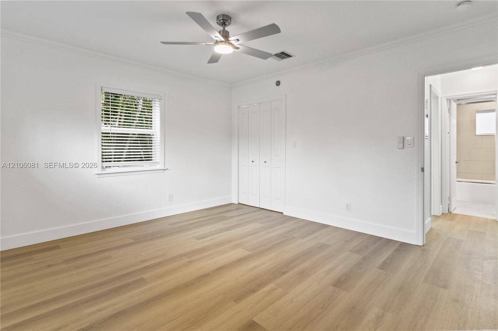 Interior space featuring wood-finish flooring, white walls, a multi-blade ceiling fan with integrated lighting, and a bifold closet