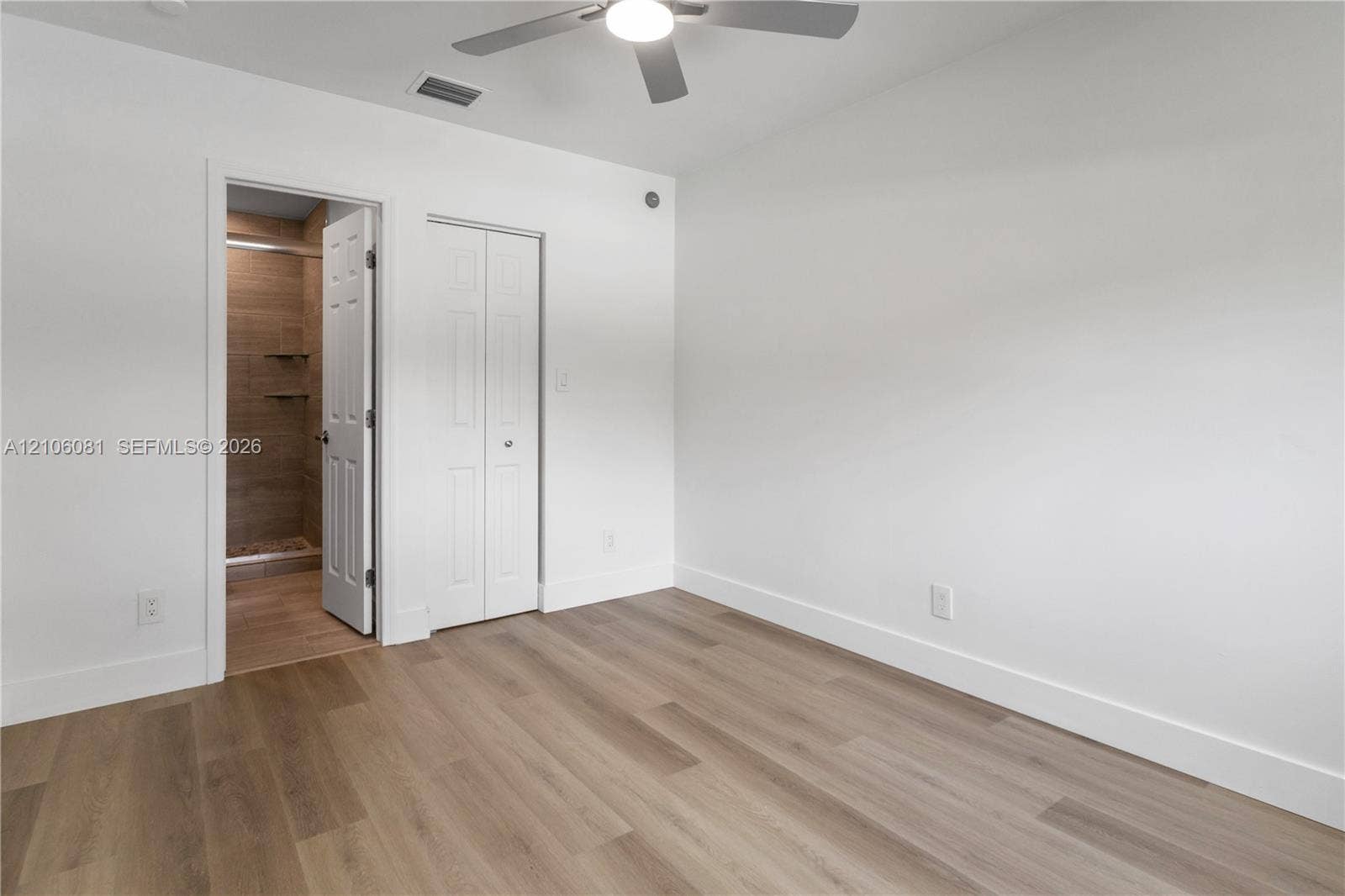 Room featuring wood-finish flooring, a ceiling fan with integrated lighting, and a bi-fold closet door