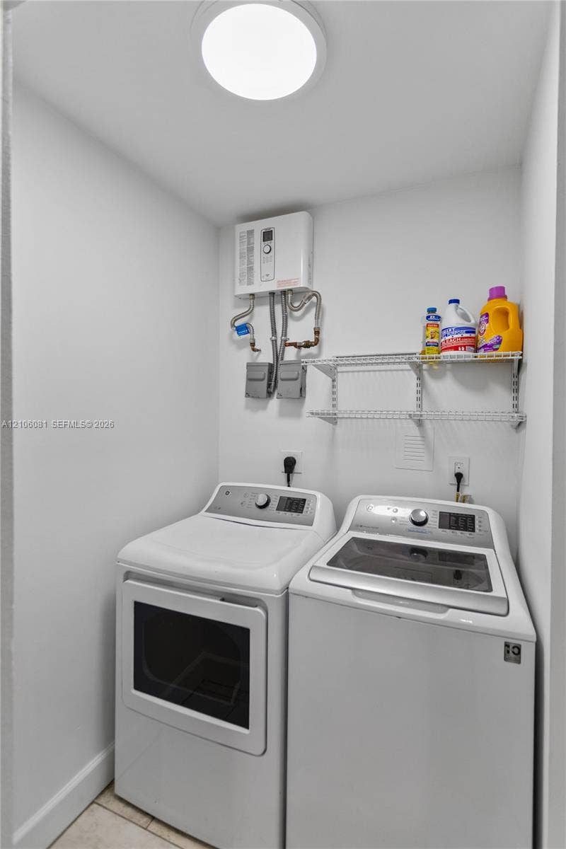 Utility space featuring a tankless water heater, white top-load washer, front-load dryer, and two-tier wire shelving