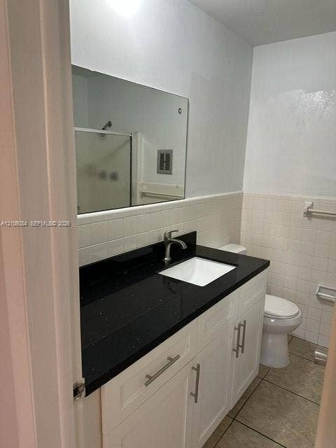 324 SE 10th Avenue, #1-8, Pompano Beach, Pompano Beach, FL 33060 Bathroom vanity featuring a dark stone countertop, integrated rectangular sink, brushed-metal hardware, white cabinetry, and a large frameless mirror