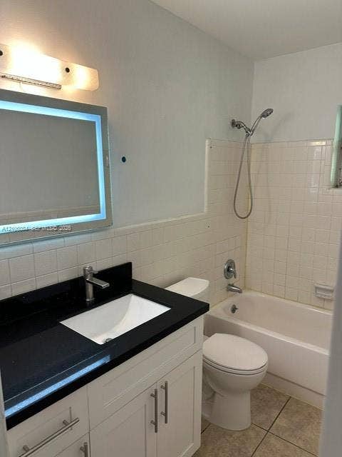 324 SE 10th Avenue, #1-8, Pompano Beach, Pompano Beach, FL 33060 Room featuring neutral wall paint, tile flooring, a horizontal window with blinds, a six-panel door, and a ceiling-mounted light fixture with a fan