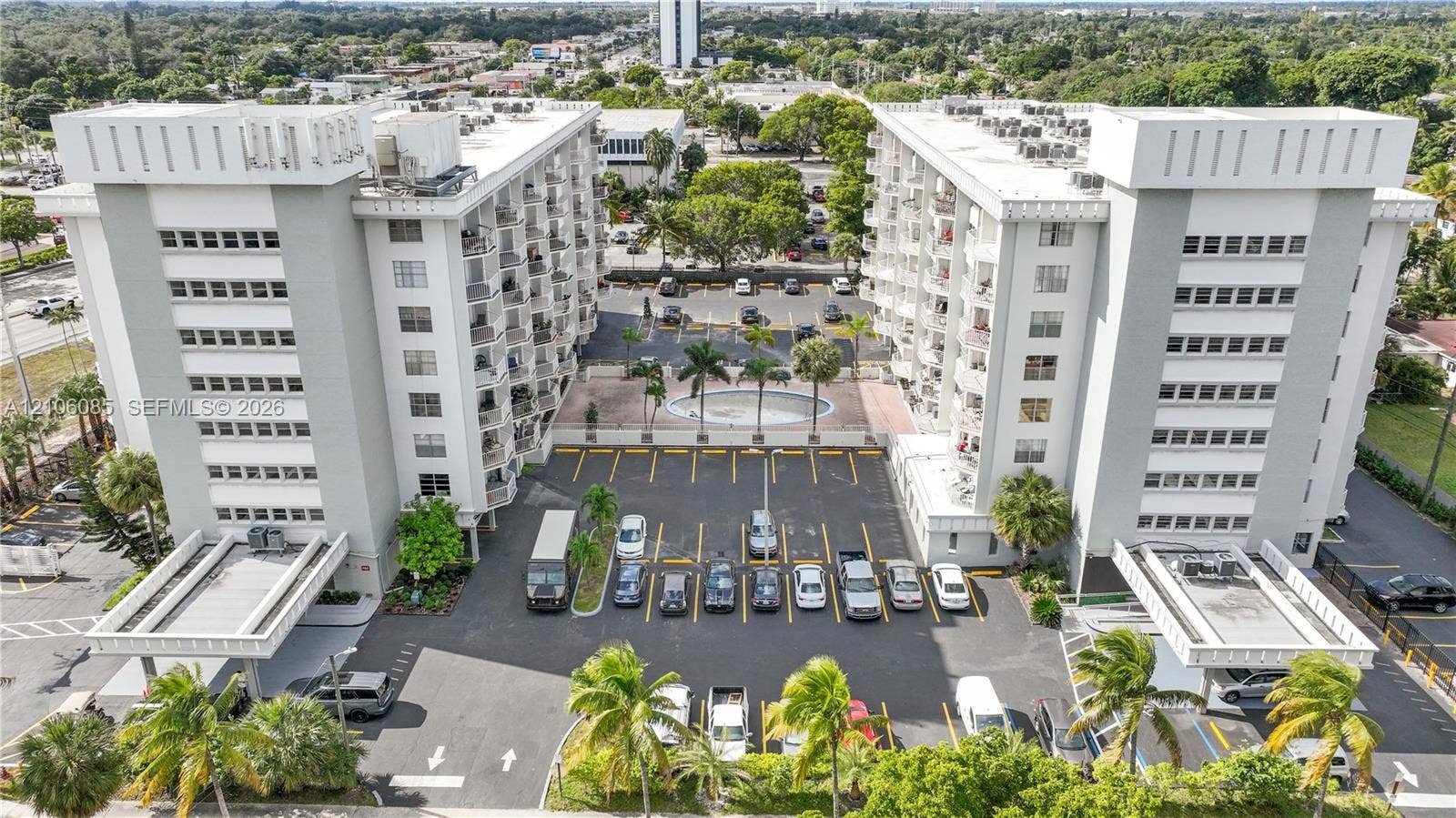 16710 NE 9th Avenue, #705, North Miami Beach, North Miami Beach, FL 33162 Multi-story residential complex featuring concrete facade, private balconies, paved surface parking, and a central circular courtyard