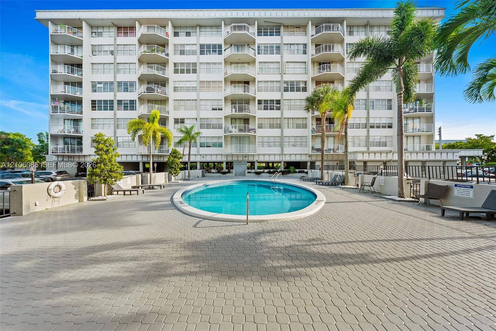 16710 NE 9th Avenue, #705, North Miami Beach, North Miami Beach, FL 33162 Multi-story residential building featuring private balconies, a central swimming pool, paved patio deck, and mature palm trees