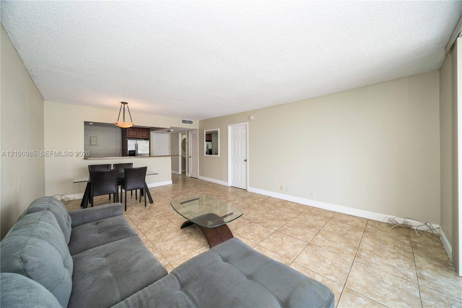 16710 NE 9th Avenue, #705, North Miami Beach, North Miami Beach, FL 33162 Open-concept interior featuring large-format tile flooring, a pass-through kitchen window, a multi-panel interior door, and a dedicated dining area light fixture