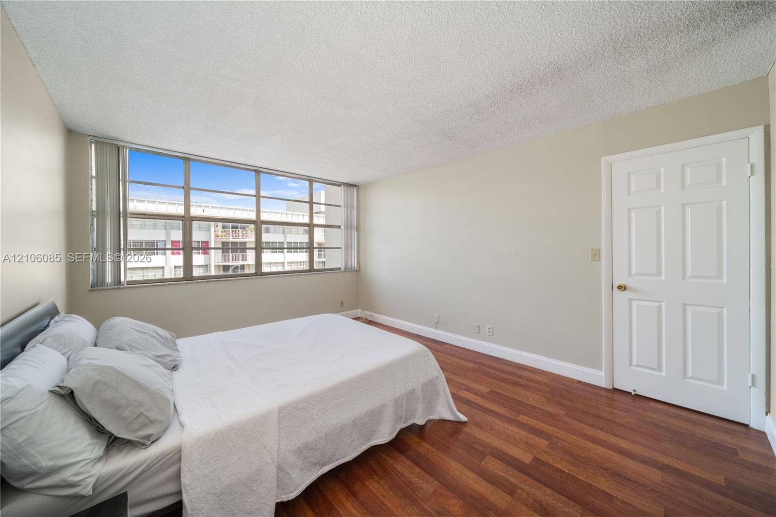 16710 NE 9th Avenue, #705, North Miami Beach, North Miami Beach, FL 33162 Interior room featuring expansive windows with vertical blinds, wood-finish flooring, and a six-panel door