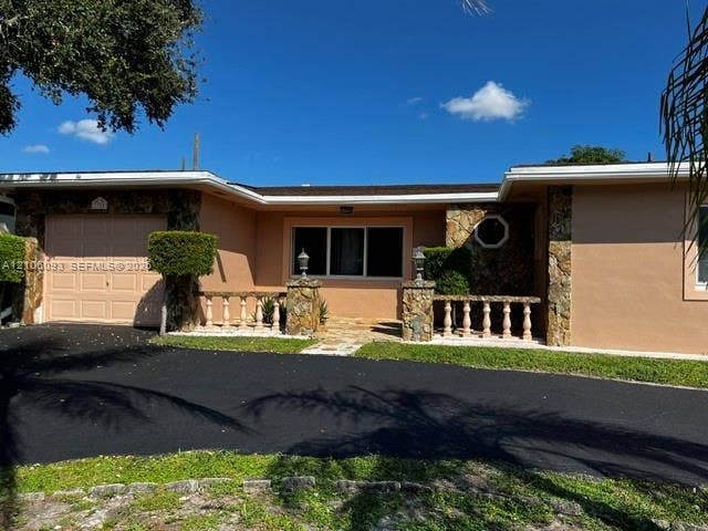 1325 N 74th Terrace, #0, Hollywood, Hollywood, FL 33024 Exterior featuring a tan stucco facade, stone masonry accents, a paved driveway, and an arched balustrade along the entry