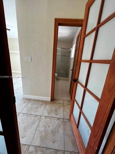 1325 N 74th Terrace, #0, Hollywood, Hollywood, FL 33024 Interior passageway featuring wood-frame French doors with frosted glass panels and neutral-toned tile flooring