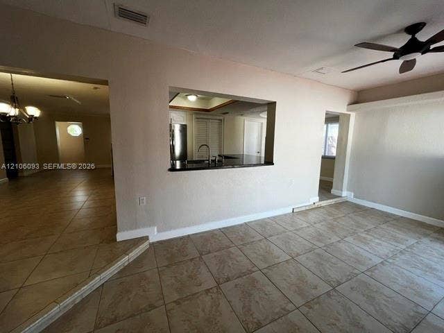 1325 N 74th Terrace, #0, Hollywood, Hollywood, FL 33024 Ceramic tile flooring, pass-through kitchen opening with a dark surface countertop, ceiling fan with light fixture, and chandelier lighting