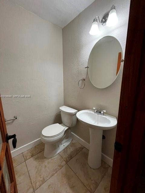 1325 N 74th Terrace, #0, Hollywood, Hollywood, FL 33024 Pedestal sink with dual-handle faucet, oval wall-mounted mirror, ceramic tile flooring, and dual-bulb light fixture