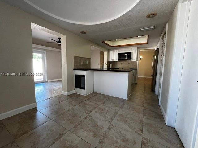 1325 N 74th Terrace, #0, Hollywood, Hollywood, FL 33024 Kitchen featuring a breakfast bar with stone-surfaced countertops, white cabinetry, integrated microwave, tiled backsplash, and neutral ceramic tile flooring